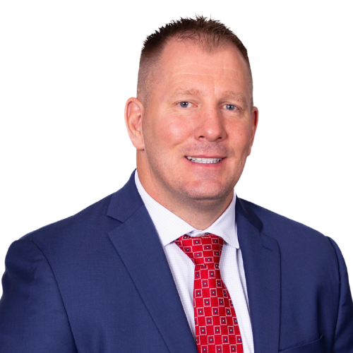 Portrait of a man in a blue suit, white shirt, and red patterned tie, smiling at the camera against a white background.